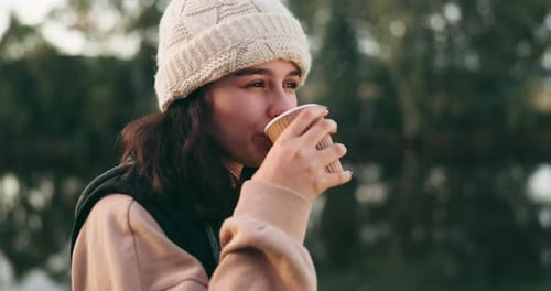 Woman Drinking from a Paper Cup Outdoors