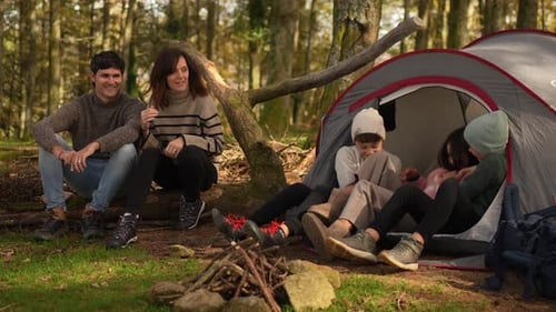 Family sitting next to bonfire enjoying weekend in the forest