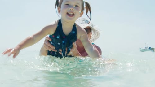 Water fun. Elderly woman swims in the warm calm sea with toddler girl and they have fun together
