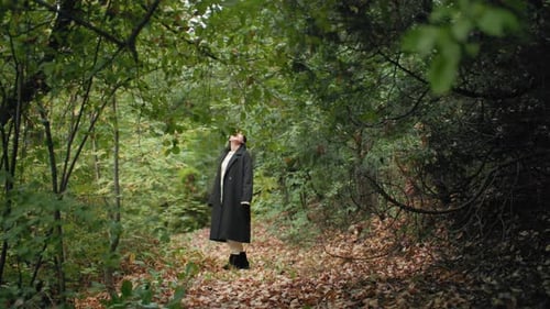 Woman standing and looking up in a forest