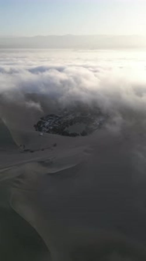 Aerial video above fog in the dunes of Huacachina Peru