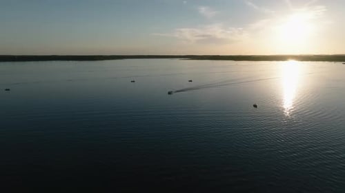aerial drone shot of boats on a large lake with the sun setting in the background