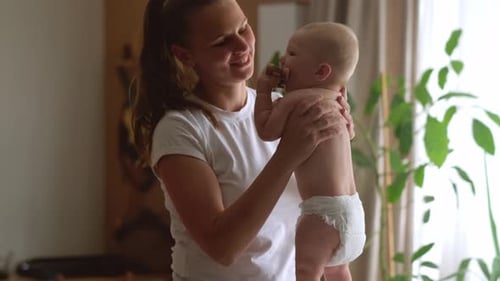 Mom and Infant Baby at Home Young Mother Leans Over Changing Table Gently Kissing Her Baby Forehead