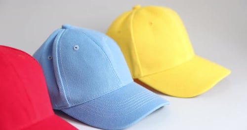 Woman taking yellow baseball cap on grey background, closeup