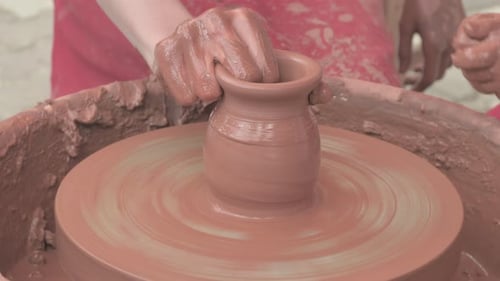 Maître fabriquant de la poterie avec son apprenti sur le tour de poterie