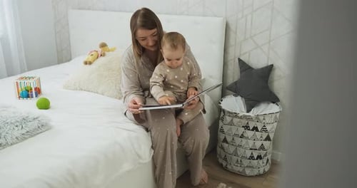 Mother reading to baby on bed at home