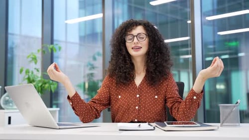 Relaxed Woman Meditating at Desk in Modern Office