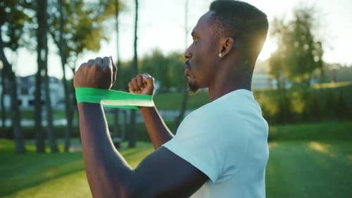 Man Exercises in Park with Resistance Band