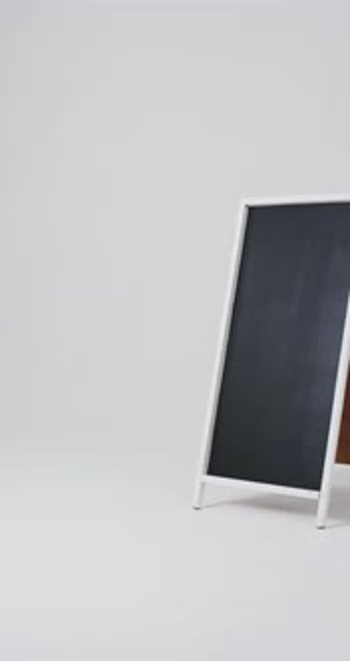 Vídeo vertical del letrero de pizarra sobre soporte blanco con espacio para copiar sobre fondo blanco