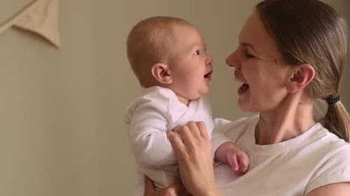 Mother and Baby Share Joyful Moment As They Smile at Each Other Baby is Held Securely in the Mother