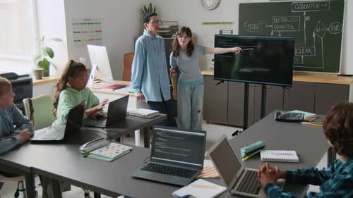 Teenage Girl with Prosthetic Arm Explaining Programming Concept to classmates