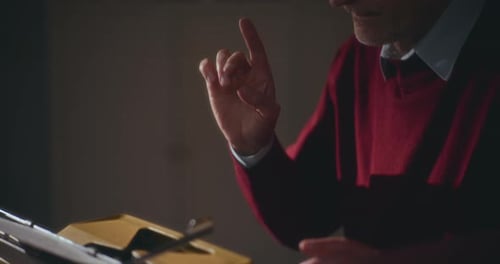 Writer Pauses at Yellow Typewriter Surrounded by Books