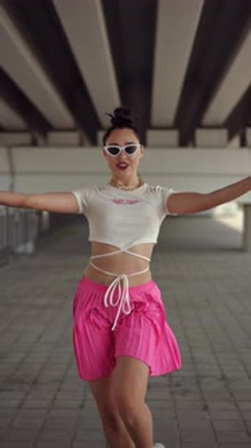 Vertical Video Modern Street Dance Under City Bridge A Cute Girl in Sunglasses and a Pink Skirt
