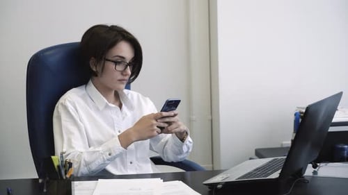 Businesswoman Using Smartphone at Office Desk