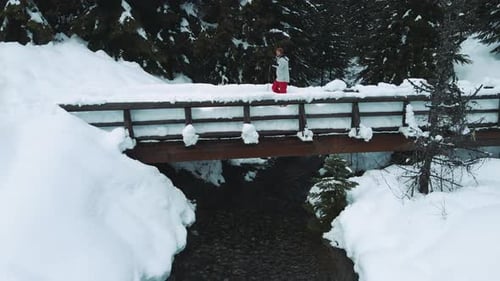 Slow Motion Snowshoe Aerial With Man Hiking Over Snowy Bridge