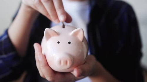 Hand putting coin in pig moneybox for saving money. Financial and invest concept. Vertical video
