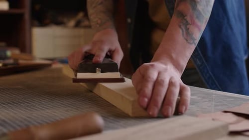 Artisan Smooths Wood Piece With Plane in Workshop