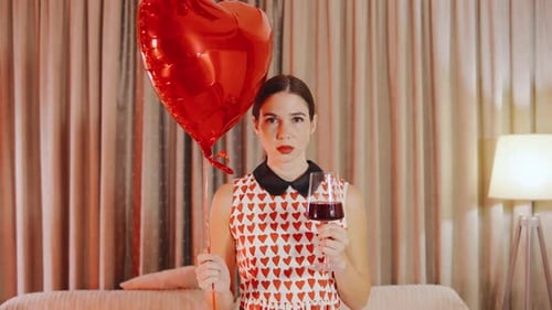 Woman Holding Balloon and Wine in Living Room