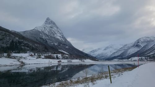 Scenic landscape covered with snow and a lake with clear and still water and big mountain peak on a