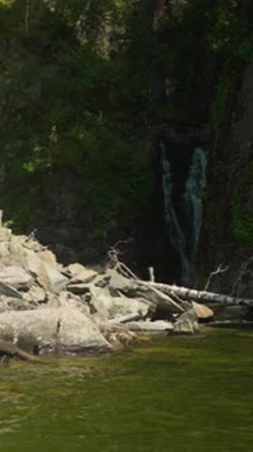 Ein kleiner Wasserstrom fließt aus dem Steinfelsen am Flussufer