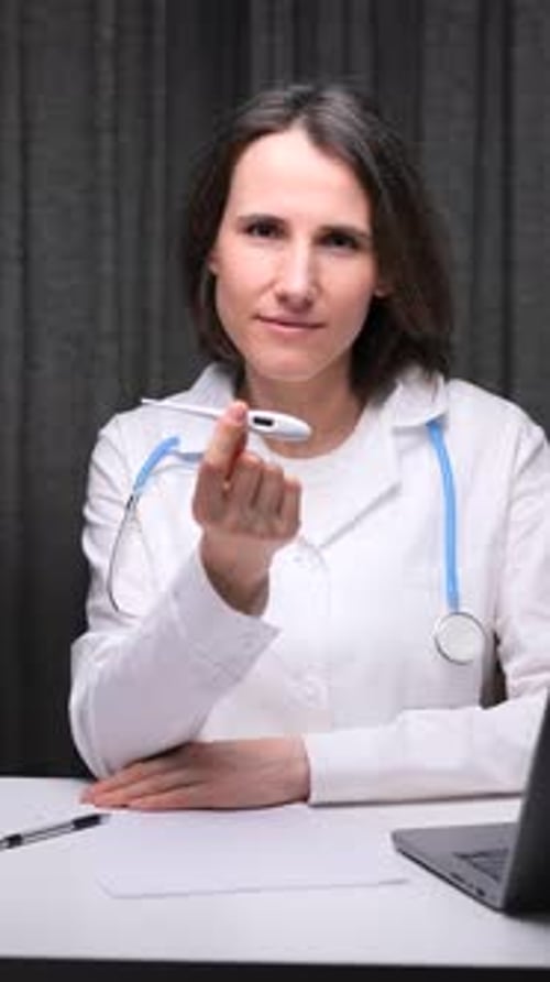 Woman Doctor Holds Thermometer in Office Setting