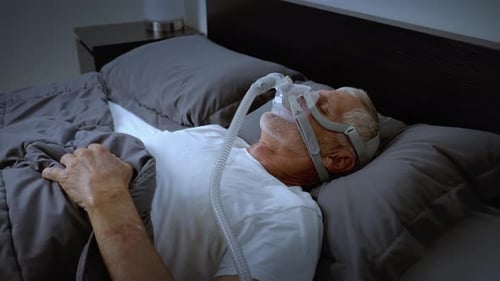 Mature adult sleeping while wearing a CPAP mask