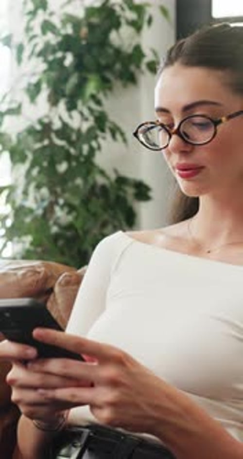 Young Woman in Glasses Using Smartphone at Home