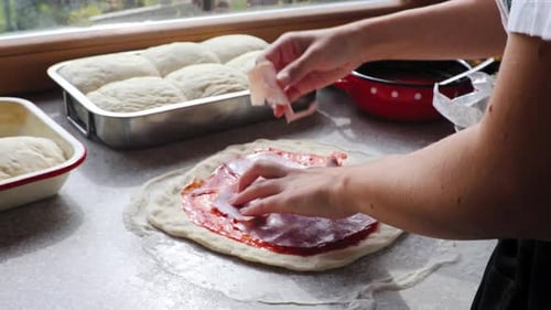 Meat ingredients used for delicious italian cuisine pizza. Putting the delicious ham slices on the d