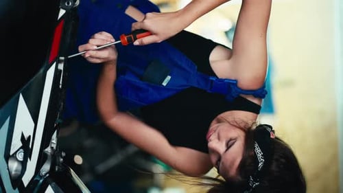 Vertical Video A Brunette Girl in a Black Top and Blue Overalls at the End of the Working Day Wipes