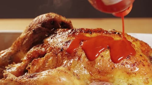 Cooked Chicken Being Drizzled with Red Sauce
