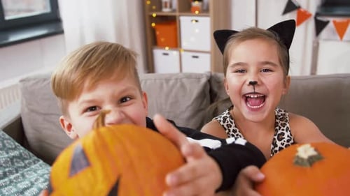 Children in Halloween Costumes Holding Pumpkins Indoors