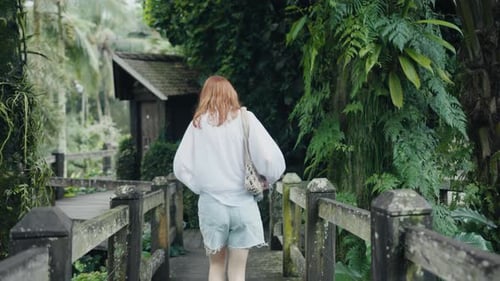 Tourist Walking on Wooden Bridge in Tropical Garden