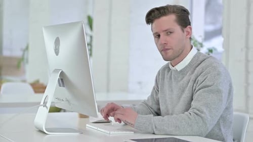 Young Adult Reacting at Computer in Workplace