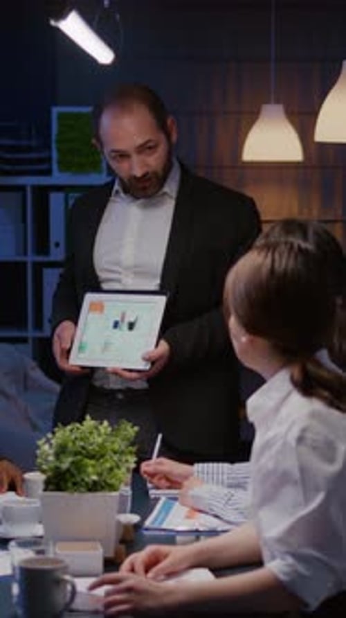 Man Shows Tablet Data to Team in Office