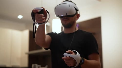 Man Uses Virtual Reality Headset and Controllers Indoors