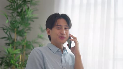 Young Adult Chatting Happily on Smartphone Indoors