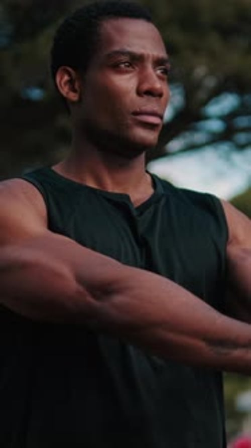 Vertical video, Muscular Black Man Stretching in the Park