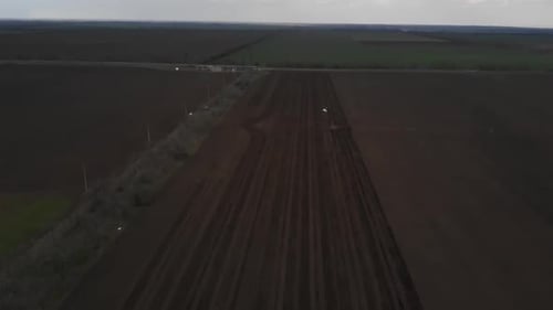 Blue tractror planting sunflower with yellow planter on the cultivated field in Ukraine
