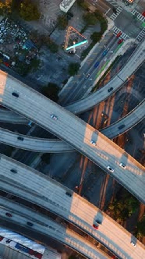 Few speedways entwining in the downtown of big city. Some cars run by the highways.