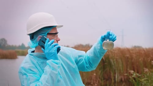 Scientist Holding Flask Talking on Phone by Lake