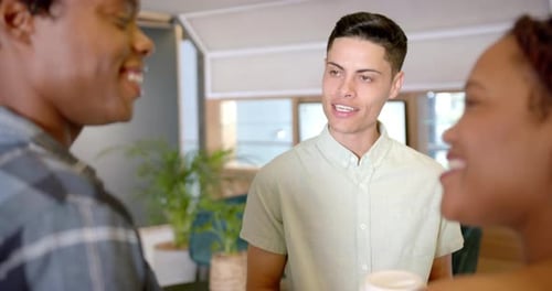 Colleagues discussing work, holding coffee cups, engaging in conversation in office