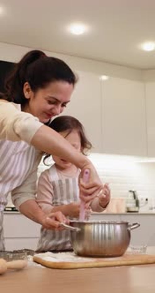 Mother and Her Little Child Daughter in Aprons Preparing the Dough