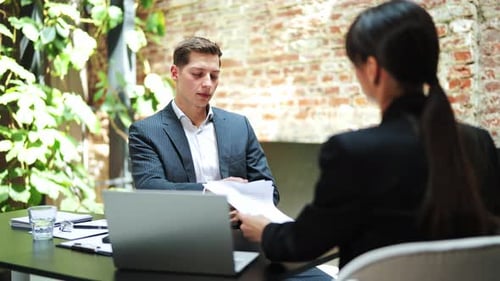 Business Meeting Businessman and Businesswoman Discuss Documents in Modern Office