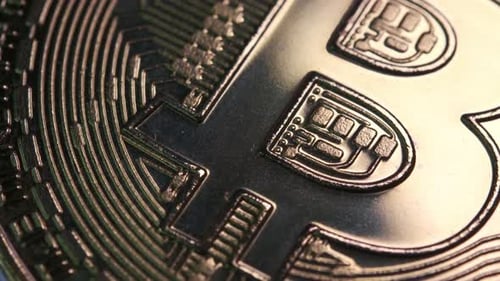 Makroaufnahme einer Kryptowährungsmünze in Bitcoin-Währung, die sich langsam mit reflektierendem Licht dreht