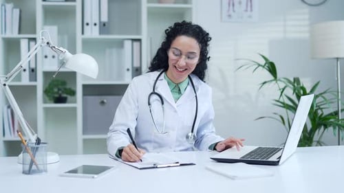 Woman Doctor Working at Desk on Laptop and Notes