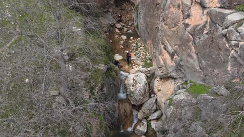 Canyoning in einer Schlucht direkt neben einem Abgrund und einem Wasserfall. Luftaufnahme beim Abstieg von einer Drohne
