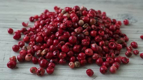 Heap of Vibrant Red Peppercorns on Wood Surface