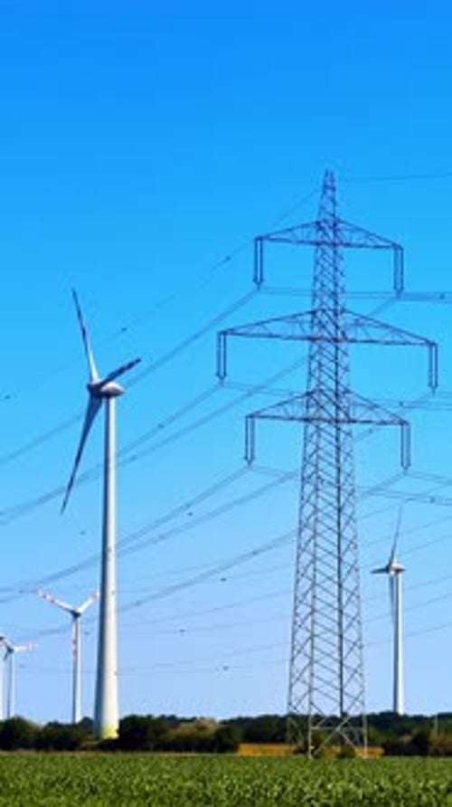 Turbinas y líneas eléctricas en cielo azul.