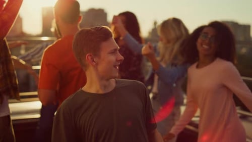 Friends Enjoying Rooftop Party Dancing at Sunset