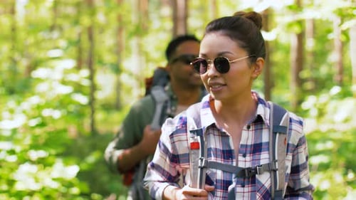 Couple Hiking Through Green Forest in Sunlight